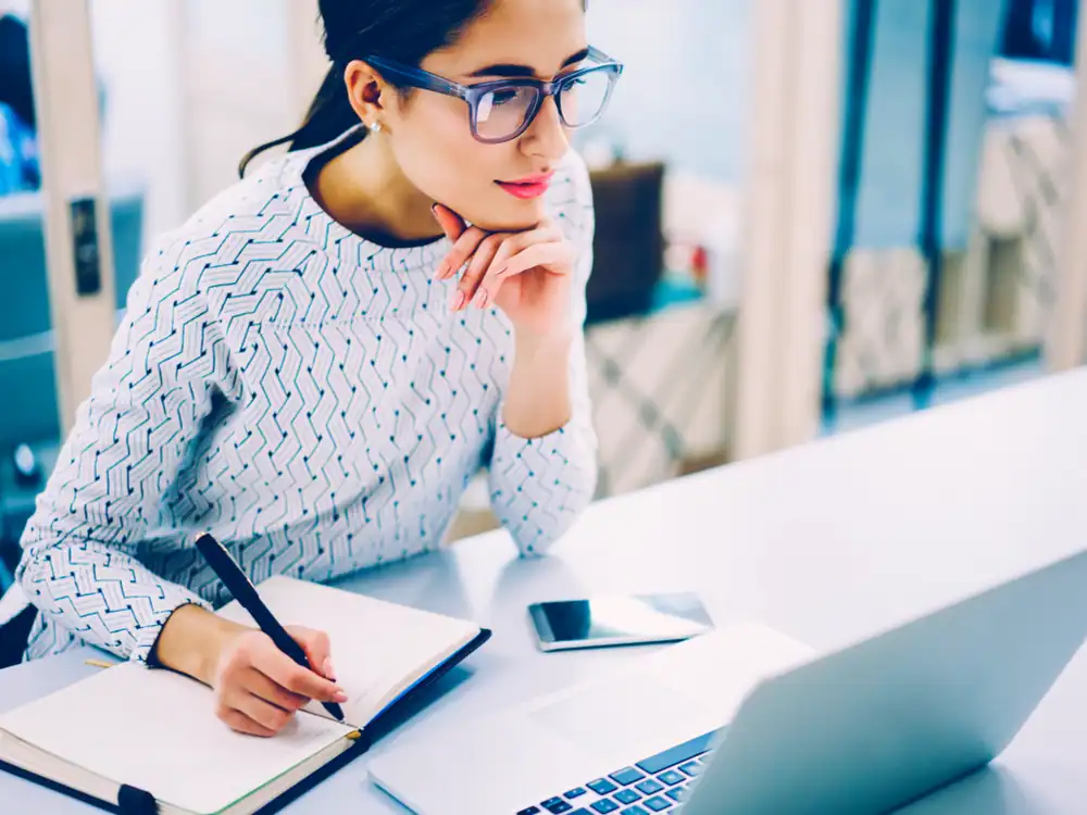 lady working, looking at the laptop while writing